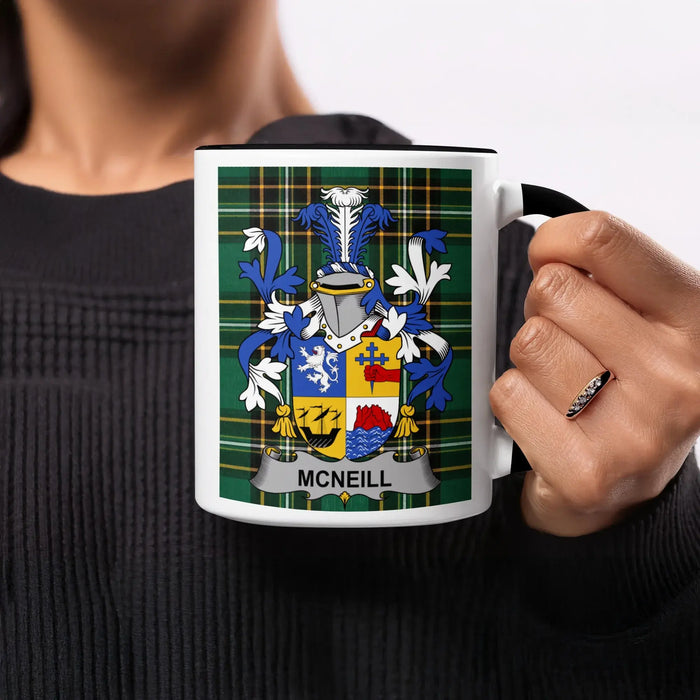 McNeill family crest on a black-handled mug held by a person.