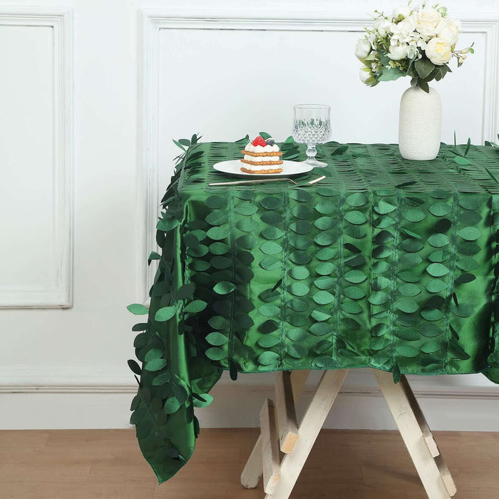 Green leaf-patterned tablecloth on a wooden table with dessert and flowers.