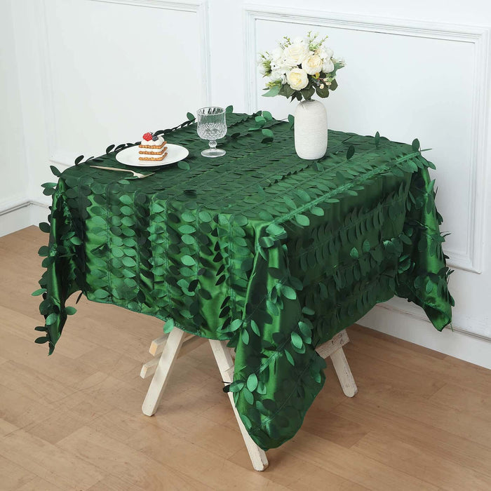 Green leaf-patterned tablecloth on a wooden table with a vase and dessert.