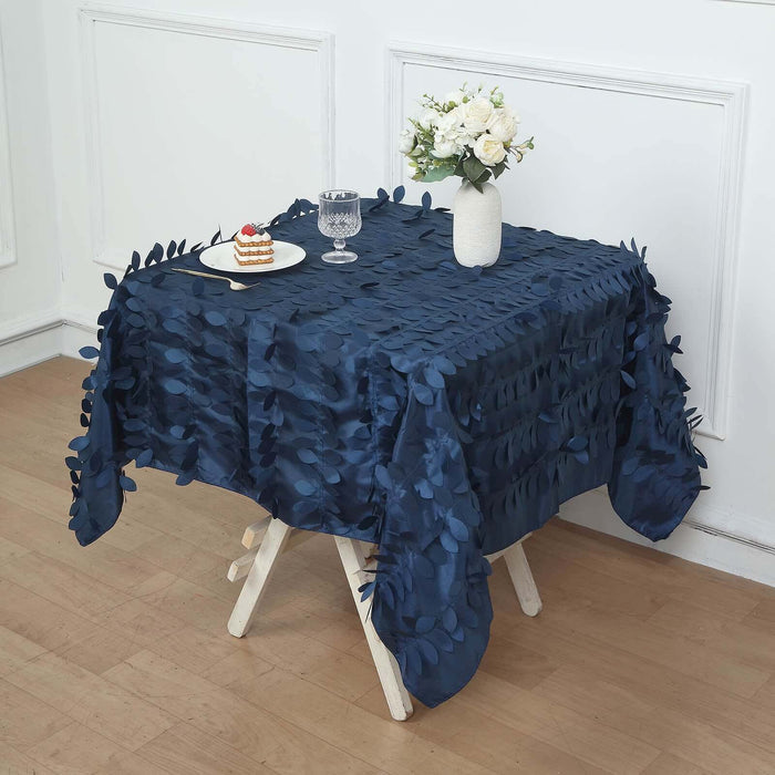 Navy blue tablecloth with leaf design on a wooden table with dessert and flowers.